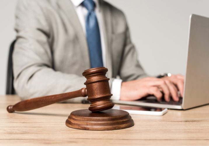 selective focus of gavel near lawyer working at laptop isolated on grey